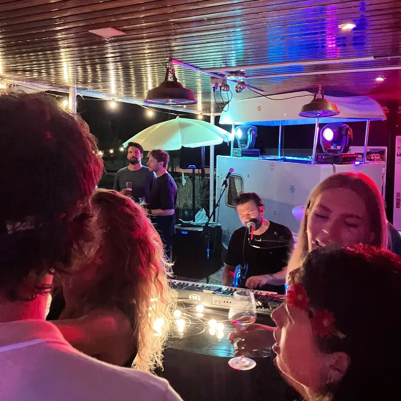 Gasten zingen mee aan een tafel terwijl de pianist op de achtergrond speelt