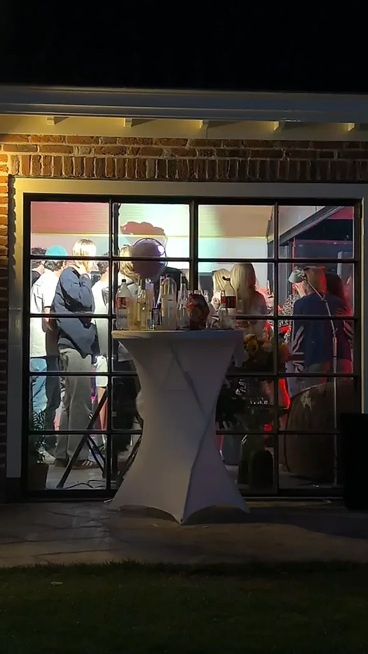 Een volle zaal gezien vanaf buiten, met gekleurd licht binnen