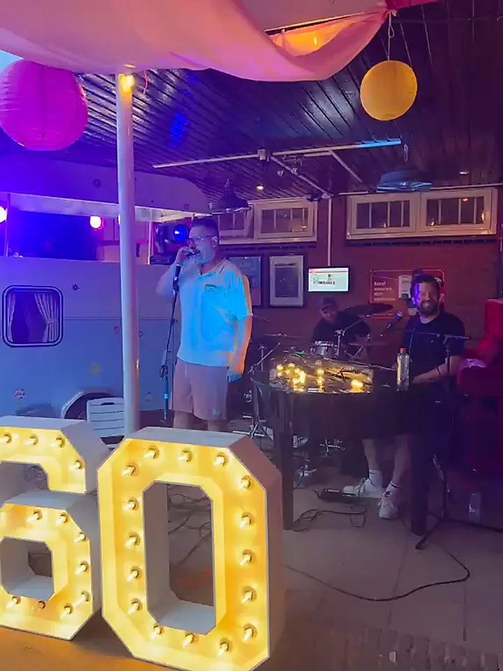 Verjaardagsfeest in de avond met verlichte 60-letters en de band